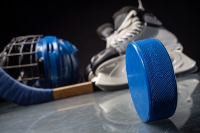 close-up on hockey puck and hockey equipment in background.