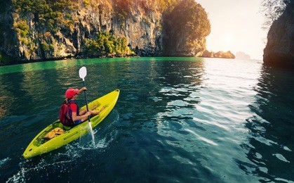 young lady paddling the kayak in the calm bay with limestone mountains