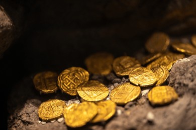 ancient gold coins from the colonial era scattered over large rocks, resembling a lost treasure. the gleaming gold contrasts with the rugged stone, evoking history, wealth, and adventure. stock photo