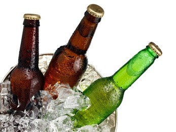 three small beer bottles in a bucket with ice close up, top view