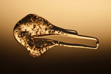 a delicious drop of 24k gold serum on a gold background.