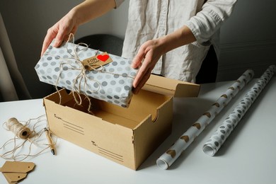 woman putting a gift for her mom into a postal delivery box to prepare it for sending