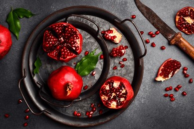 metal tray with ripe red pomegranates and pomegranate seeds. on a dark background. close up.