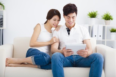 asian couple on sofa with tablet computer