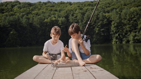 two kids engaging in a fun fishing activity at a serene lakeside dock, enjoying nature