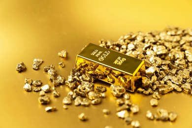 gold nuggets and bar on shiny background, closeup