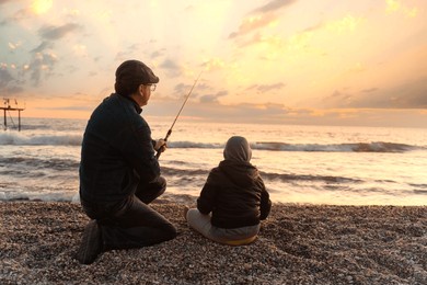 
father and son on a fishing trip, back view portrait of adult man and  boy fishing together on the beach