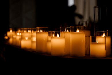 close-up of several artificial candles, against a dark background