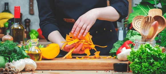 cook collects pumpkin peelings for recycling. cozy kitchen with wooden table, kitchenware, vegetables, herbs and ingredients for cooking. healthy vegan eating, zero waste, recipes, food blogging 