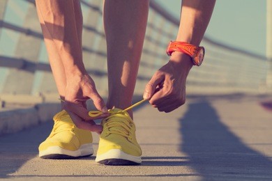 urban jogger tying his running shoes on a big bridge.
