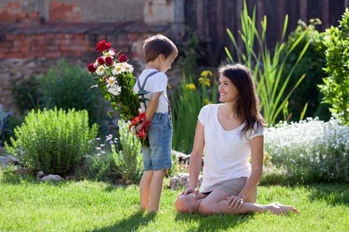 beautiful kid and mom in spring park, flower and present. mothers day celebration concept