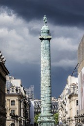 vendome column with statue of napoleon bonaparte against background of a stormy sky, place vendome in paris, france. vendome column has 425 spiraling bas-relief bronze plates were made out of cannon.
