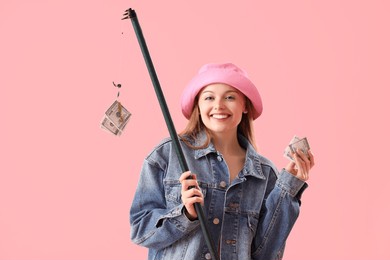 happy young woman with fishing rod and money on pink background