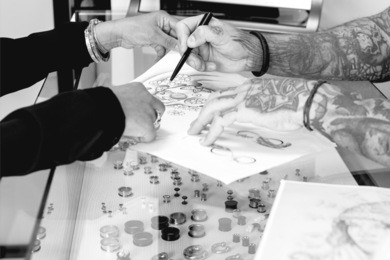 detail of a tattoo design of a tattoo artist is showing to a young female customer the tattoo design before the tattoo session at the tattoo shop - focus on the tip of the pen