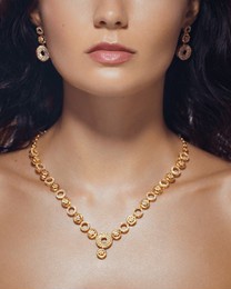 elegant close-up of a woman's neck and face with a sparkling gold necklace and earrings. high quality jewelry image perfect for fashion, accessories, and luxury branding promos.