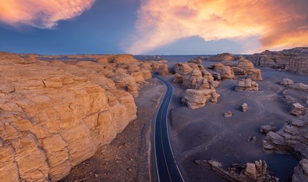 a road winding through the yardang landform mountain at sunset. famous dahaidao no man's land natural landscape in xinjiang, china.