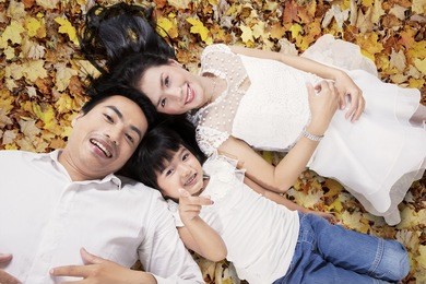 unique perspective of lovely family lying down on the autumn leaves while looking at the camera