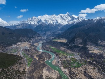 nyingchi, tibet, china - 7th april 2025 - beautiful peach blossoms along yarlung zangbo river and high angle view of namjagbarwa peak