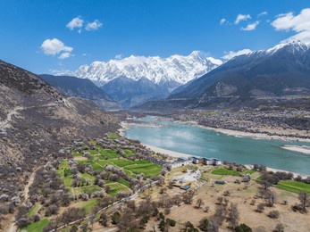 nyingchi, tibet, china - 7th april 2025 - beautiful peach blossoms along yarlung zangbo river and view of namjagbarwa peak and its reflection