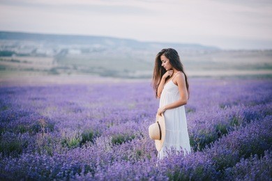 beautiful young woman in a white dress posing in a lavender field