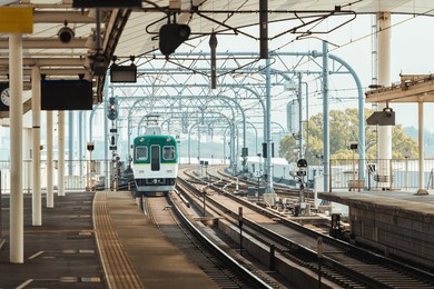 electric railway iconic train with intricate metal structure and multi tracks arrival to station at kyoto, japan