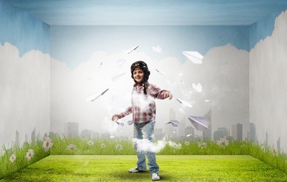 little cute boy in pilot helmet and paper airplanes flying around