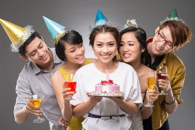 teenage girl holding a cake with her friends behind