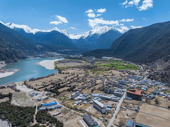 nyingchi, tibet, china - 7th april 2025 - aerial view of a normal village in tibet along snow mountains and yarlung zangbo river