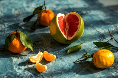 pomelo red inside with tangerine and lemons lies on blue concrete