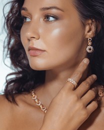refined close-up of a woman with glowing skin, wearing gold earrings, necklace, and a ring. high quality beauty and fashion image perfect for luxury jewelry or skincare promos.