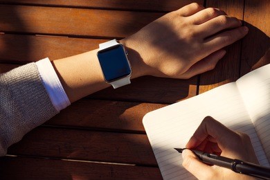 women hands with smart watch working on table