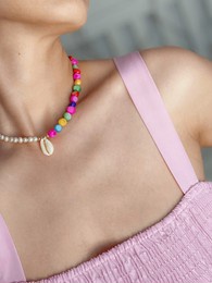 handmade necklace with pearls, shells and colorful stones on a woman's neck in a pink dress