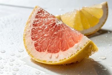 a vibrant close-up captures a glistening grapefruit wedge, its pink flesh contrasting with the yellow lemon slice in the background. water droplets enhance the image's freshness.