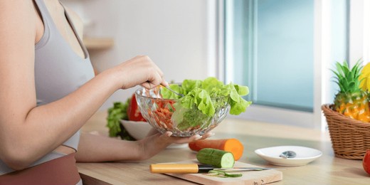 wellness and meal preparation. young woman mixing fresh salad ingredients in a modern kitchen.