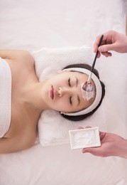 spa therapy for young asian woman receiving facial mask at beauty salon.