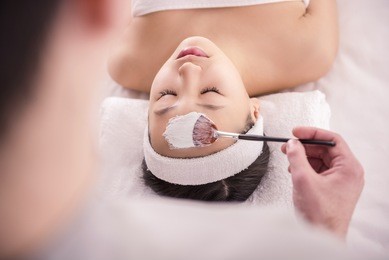 spa therapy for young asian woman receiving facial mask at beauty salon.