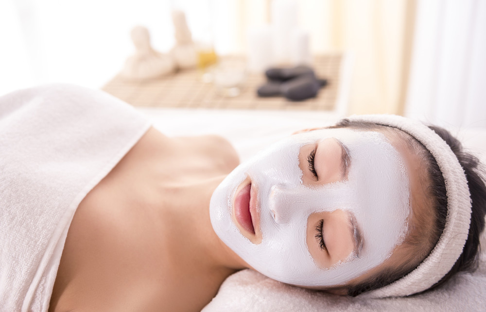 spa therapy for young asian woman receiving facial mask at beauty salon.