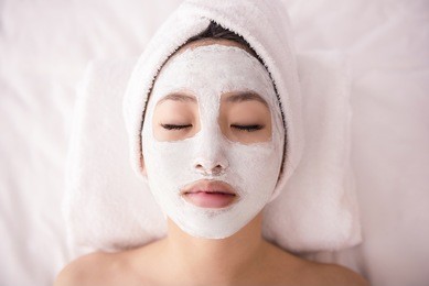 spa therapy for young asian woman receiving facial mask at beauty salon.