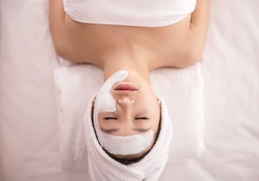 spa therapy for young asian woman receiving facial mask at beauty salon.