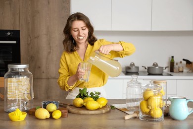 young woman pouring lemonade into glass in kitchen