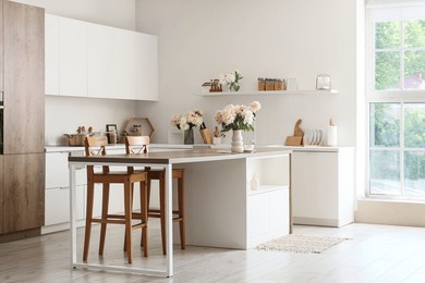 interior of stylish kitchen with island table and beautiful peonies