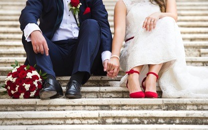 unrecognizable young wedding couple holding hands as they enjoy romantic moments outside on the stairs