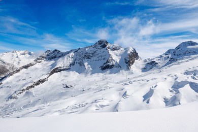 snowy ski slopes and alpine peaks under a clear blue sky in saas-fee, switzerland, panoramic view of winter landscape with fresh snow, groomed pistes, and dramatic mountain scenery