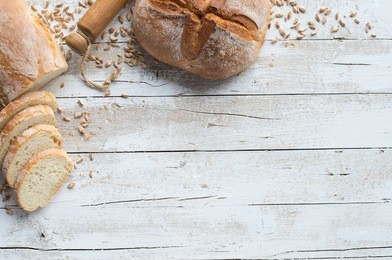 loafs of bread and rolling pin on rustic table with grain
