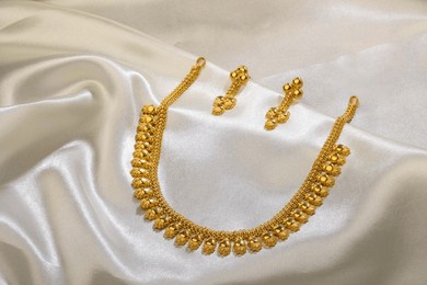 gold necklace on white satin background 