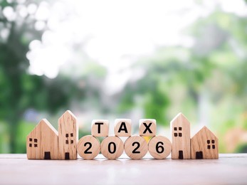 miniature house, wooden blocks with the word tax and number 2026. the concept about saving money and manage time to payment tax for house, property investment, house mortgage, real estate in year 2026
