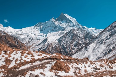 stunning himalayan landscape around annapurna base camp, nepal, with snow-covered peaks, rugged trails, and alpine scenery under a clear blue sky."