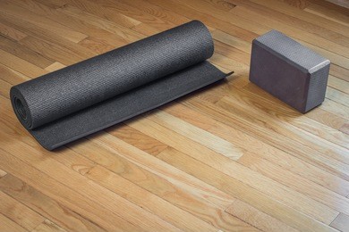 a black yoga mat rolled up next to a brown yoga mat on a wooden floor