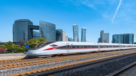 high-speed train passing through modern city buildings