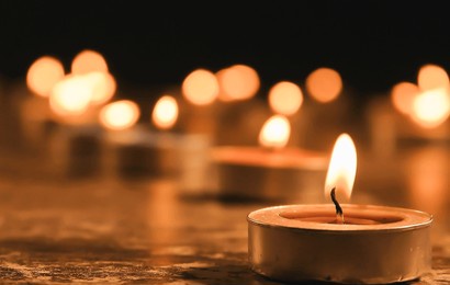 burning candles on dark surface against black background, closeup